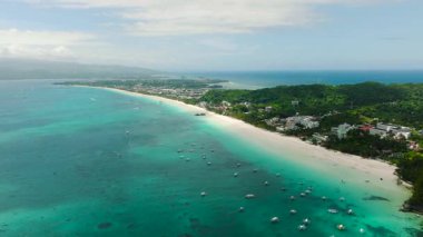Bereketli yeşil tropikal sahil güneşli bir gökyüzünün altında okyanusun berrak mavi sularıyla buluşuyor. Boracay Adası, Filipinler.