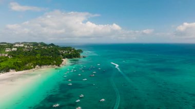 Beyaz kumlu sahilleri, turkuaz suları ve güneşli bir gökyüzünün altında demirlemiş tekneleri olan kıyı manzarası. Boracay Adası, Filipinler.
