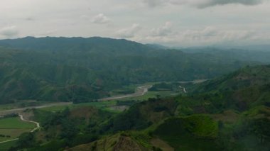 Yeşil tepeleri ve ormanı olan bir dağ bölgesi. Nehrin yakınındaki tarım arazisinin üzerinde tarım arazileri. Mindanao, Filipinler.