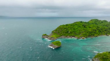 Turkuaz sular ve uçsuz bucaksız ufuklarla çevrili yemyeşil bir kayalık ada. Ilig Iligan Sahili. Boracay Adası, Filipinler.