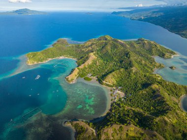 Tropik ada, gök mavisi su mercan kayalıklarını ve mercan adalarını çevreledi. Uyuyan Dinozor Adası. Mati, Davao Oriental. Filipinler.