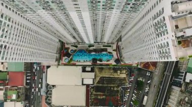 Şehirdeki canlı bir havuz alanını çevreleyen yüksek binaların en üst görüntüsü. Metro Manila, Filipinler.