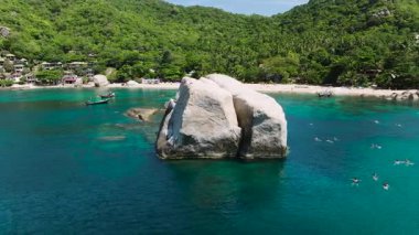 Berrak turkuaz suyla çevrili kayalık formasyon yemyeşil ve arka planda kumlu bir plaj. Ao Tanote Körfezi. Koh Tao, Tayland.