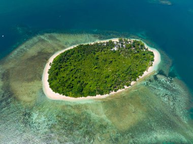 Etrafı mercan resifleriyle çevrili kumlu bir sahil ve gök mavisi bir suyla adanın üzerinde uçuyor. Mindanao, Filipinler.