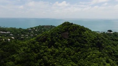 Yoğun tropikal ağaçlarla kaplı yeşil tepe villalarla ve uzaktaki kıyı şeridiyle çevrili. Ko Samui, Tayland.