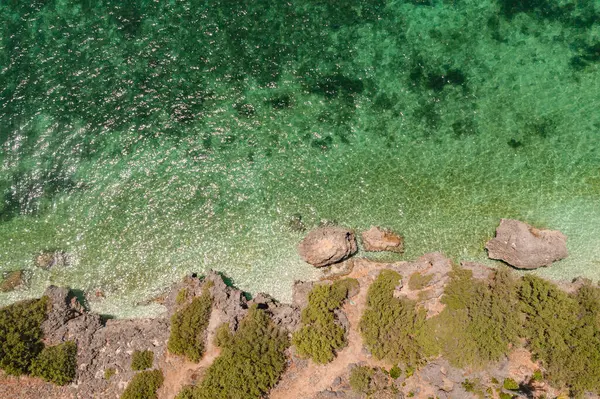 Güneş ışığı yansımalı berrak deniz suyunun en üst görüntüsü. Kıyı şeridinde kayalar olan tropik bir ada. Bantayan Adası. Cebu, Filipinler.