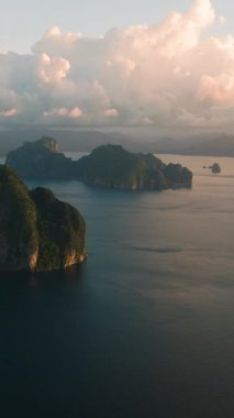 El Nido 'da alacakaranlıkta bir grup ada. Gökyüzü ve bulutlar aydınlandı. Palawan, Filipinler. Dikey görünüm.