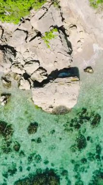 Kayalık sahilde dalgalar, Carabao Adası 'nda turkuaz deniz suyuyla kıyı şeridi. San Jose, Romblon. Filipinler. Dikey görünüm.