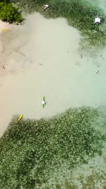 Kristal berrak suyun üzerinde yüzen tekneler. CYC Sahili 'ndeki mercan kayalıkları. Coron, Palawan. Filipinler. Dikey görünüm.
