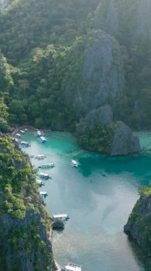 Kayangan Gölü etrafındaki kireçtaşı dağlarının insansız hava aracı görüntüsü. Sahilde ada turu yapan tekneler. Coron, Palawan. Filipinler. Dikey görünüm.