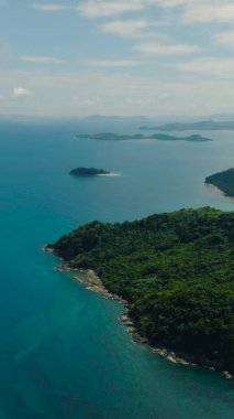 Mercan resifli mavi denizi olan tropik bir ada. Mavi gökyüzü ve bulutlar. El Nido, Palawan. Filipinler. Dikey görünüm.