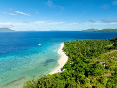 Temiz deniz suyuyla beyaz kumlu sahil. Mavi gökyüzü ve bulutlar. Logbon Adası. Romblon, Filipinler.