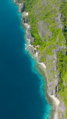 Tapiutan Adası ile Matinloc Adası arasındaki mavi deniz. El Nido, Palawan 'daki beyaz kumlu plaj. Filipinler. Dikey görünüm.