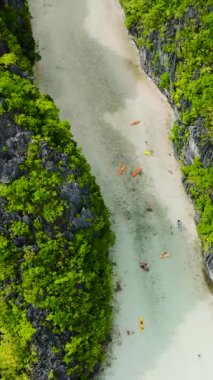 Miniloc Adası 'ndaki büyük göl. Deniz suyunda kayıklar ve kanolar akıyor. El Nido, Filipinler. Palawan 'da. Dikey görünüm.
