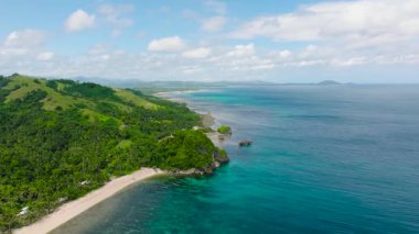Canlı yeşil tepeler, palmiye ağaçları ve berrak mavi bir okyanusa sahip kıyı manzarası. Santa Fe, Tablo, Romblon, Filipinler.