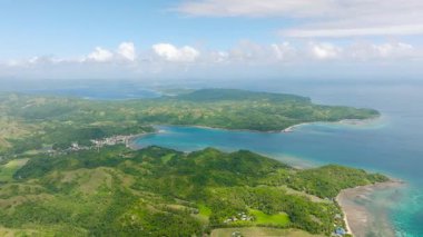 Sahil şeridi boyunca yuvarlanan yeşil tepelerin ve turkuaz suların açık gökyüzü manzarası. Santa Fe, Tablo, Romblon, Filipinler.