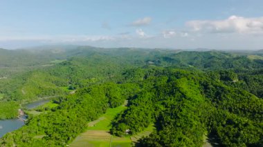 Tropikal tepelerin panoramik manzarası ve dağınık bulutlu açık mavi gökyüzünün altındaki yeşil vadiler. Tablolar Adası, Romblon, Filipinler.