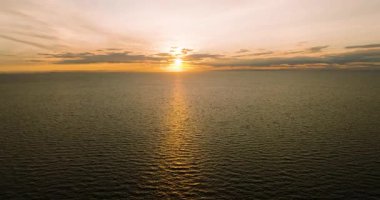 Gökyüzüne yayılmış yumuşak bulutlarla, sakin okyanusa yansıyan altın gün batımı. Koh Tao, Tayland.