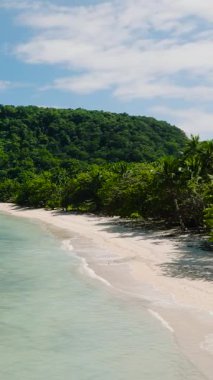 El Nido, Palawan 'daki kumlu sahilde açık okyanus dalgaları. Filipinler. Dikey görünüm.