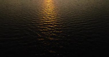 Okyanus dalgaları batan güneşin sıcacık ışığı altında parlıyor. Huzurlu bir manzara yaratıyor. Koh Tao, Tayland.