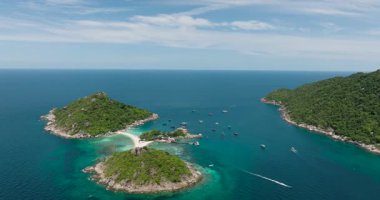 Etrafı turkuaz sularla ve yakınlarda yüzen teknelerle çevrili yemyeşil adaların manzarası. Nang Yuan, Tayland.