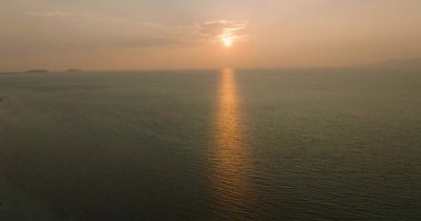 Altın saat boyunca geniş okyanus manzarası. Gün batımının sakin suya yansıması. Huzurlu bir atmosfer yaratıyor. Ko Pha Ngan, Tayland.