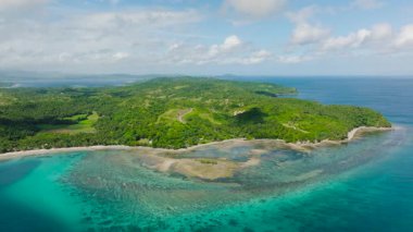 Berrak turkuaz sular, mercan resifleri ve parlak bir gökyüzü altında yemyeşil tropikal kıyı şeritleri. Santa Fe, Tablo, Romblon, Filipinler.