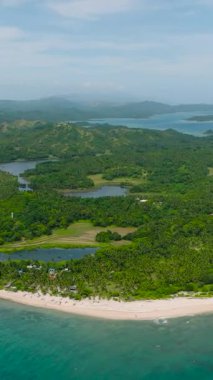 Okyanus dalgaları, turkuaz deniz suyu ve insansız hava aracı manzaralı beyaz kumlu sahil. Santa Fe, Tablas, Romblon. Filipinler. Dikey görünüm.