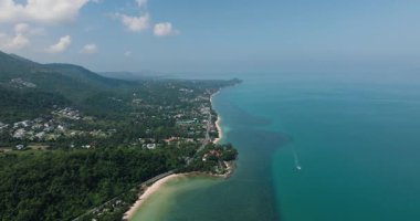 Yeşil tepeli kıyı şeridi ve parlak mavi gökyüzünün altında kristal berrak su. Ko Samui, Tayland.