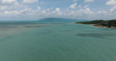 Turkuaz sular bulutlu bir gökyüzünün altındaki uzak bir adaya uzanıyor. Ko Samui, Tayland.