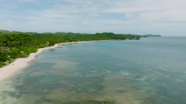 Turkuaz suları ve yeşil tepeleri olan geniş kumlu bir sahil şeridi. Santa Fe, Tablo, Romblon, Filipinler.