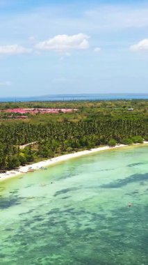 Hindistan cevizi ağaçları ve beyaz kumları olan tropik bir sahil. Bantayan Adası 'ndaki mercanlar ve balıkçı tekneleri. Cebu, Filipinler. Dikey görünüm.