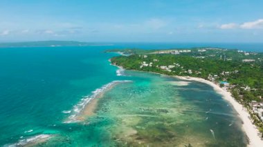 Parlak bir gökyüzünün altında turkuaz suları ve canlı mercan resiflerini gösteren okyanus yüzeyinin havadan görünüşü. Boracay Adası, Filipinler.