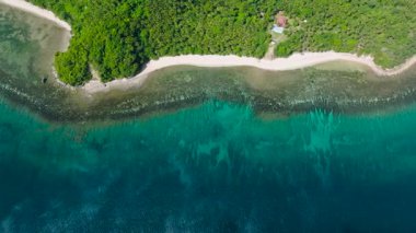 Bereketli yeşil bitki örtüsü ve kristal berrak mavi sularla çevrili, beyaz kumlu tropik bir sahil. Santa Fe, Tablo, Romblon, Filipinler.