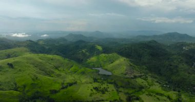 Tropikal manzara: Dağların ve mavi gökyüzünün arka planında bitkiler olan tarım arazisi. Mindanao, Filipinler.