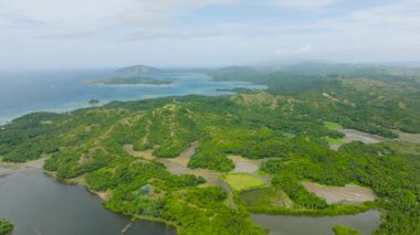 Verdant Hills açık mavi okyanusla buluşuyor, yeşillik ve tarım arazisiyle benekli. Santa Fe, Tablo, Romblon, Filipinler.