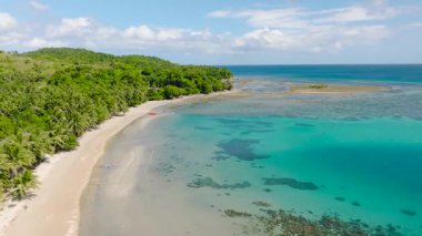Bereketli yeşillik ve palmiye ağaçlarıyla çevrili el değmemiş tropikal bir sahil boyunca mercan resifleri olan gök mavisi sular. Santa Fe, Tablo, Romblon, Filipinler.