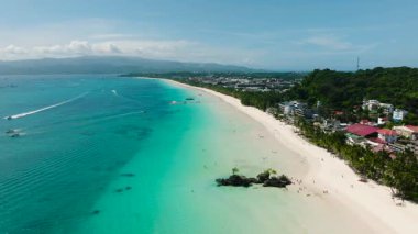 Turkuaz sularla çevrili tropik plaj ve berrak gökyüzünün altındaki yemyeşil tepeler. Boracay Adası, Filipinler.