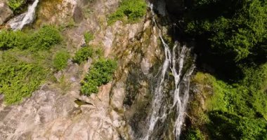 Yoğun tropikal bitki örtüsüyle çevrili engebeli kayalık uçurumların üzerinden akan şelale. Na Mueang, Ko Samui, Tayland.