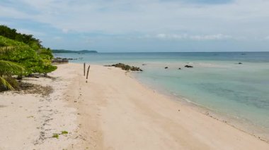 Açık bir gökyüzünün altında ufuk boyunca uzanan sakin turkuaz suları olan terk edilmiş kumlu bir sahil şeridi. Santa Fe, Tablo, Romblon, Filipinler.
