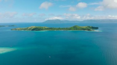 Güneşli bir gökyüzünün altında canlı mavi denizle çevrili yeşil bitki örtüsü olan pitoresk bir ada. Logbon Adası, Romblon, Filipinler.