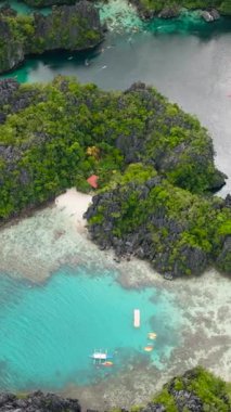 Miniloc Adası 'nda tekneleri ve açık deniz suyu olan sahil ve gölcükler. El Nido, Filipinler. Palawan 'da. Dikey görünüm.