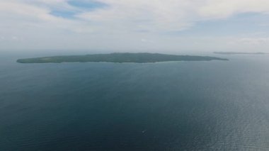 Bulutlu bir gökyüzünün altında sakin mavi okyanusla çevrili bir ada. Carabao Adası, Romblon, Filipinler.