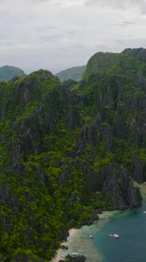 Miniloc Adası 'ndaki Beyaz Kum Sahili ve Tekneleri. El Nido, Palawan. Filipinler. Dikey görünüm.