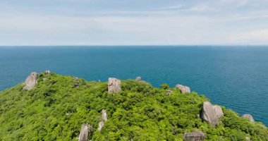 Açık okyanus manzarası, yeşil tepe ve parlak güneşli bir gökyüzünün altında büyük kayalar. Koh Tao, Tayland.