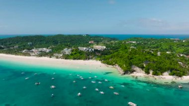 Turkuaz sular ve yemyeşil ve küçük teknelerle çevrili kumlu bir sahil. Diniwid Sahili, Boracay Adası, Filipinler.