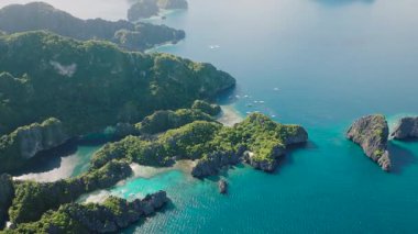 Etrafındaki uçurumlar, gölcüklerin durgun sularında güneş yansımalarıyla koruyucu bir kucaklama oluşturur. Miniloc Adası. El Nido, Filipinler. Palawan.