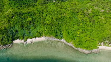 Küçük kumlu bir plajın drone görüntüsü kayaların arasına sıkışmış durumda. El Nido, Palawan, Filipinler.