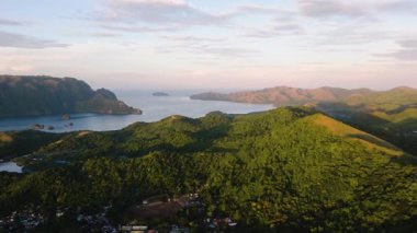 Tropikal yeşil tepeler ve günbatımı yansımalı tropikal ada yerleşim alanı. Coron, Palawan, Filipinler.