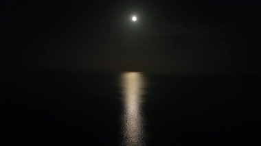 Hilal, gece sakin ve rahatlatıcı denize yansıyor. Gece sahnesi.